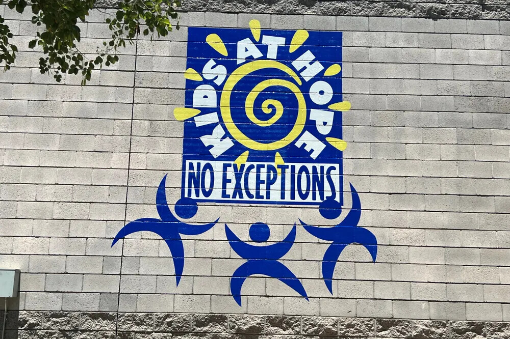 Blue and yellow mural with figures and lettering on a block wall